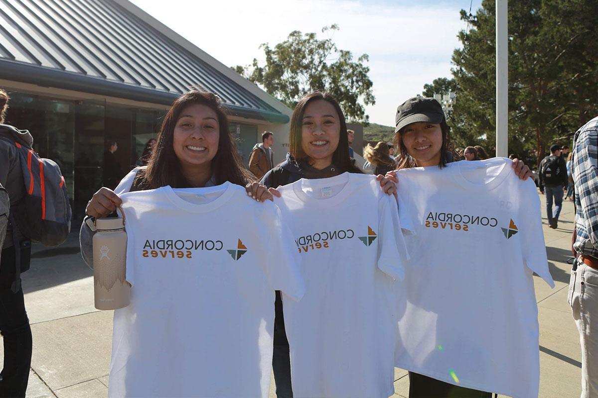 Three students showing their Concordia serves shirts